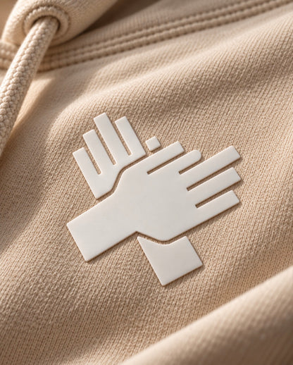     White silicone crossed-hands logo on bone cream hoodie
